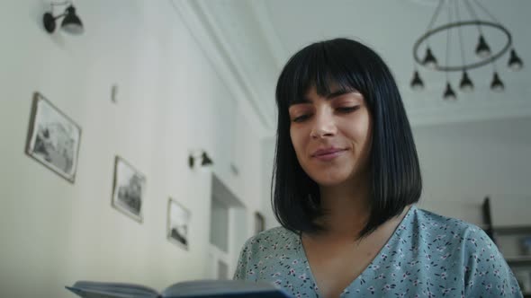 Happy Woman Reads a Book in the Library Chooses Books From the Shelf