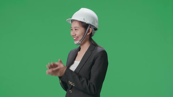 Side View Of Smiling Asian Female Engineer With Safety Helmet Clapping Her Hands In The Green Screen