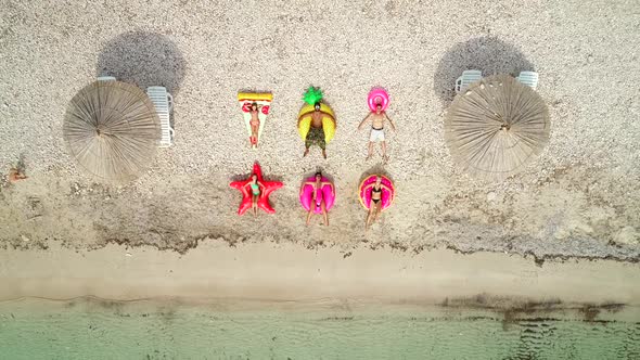 Aerial view of people lying on big inflatable mattresses on beach.