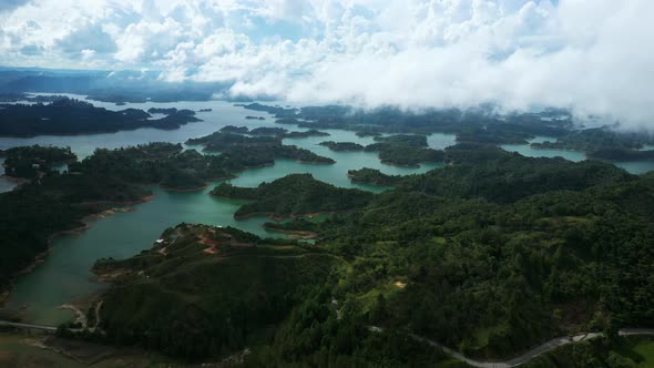 Slow cinematic aerial footage over the green landscape of Guatape lake in Colombia.