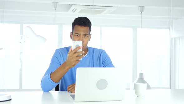 African Man Using Smartphone, Browsing online at Work