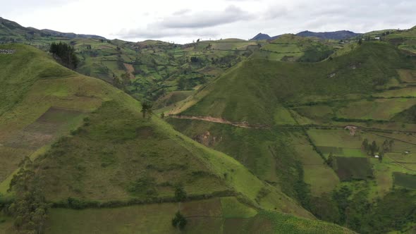 Aerial view flying towards the slope of a in green grass covered hill in a valley