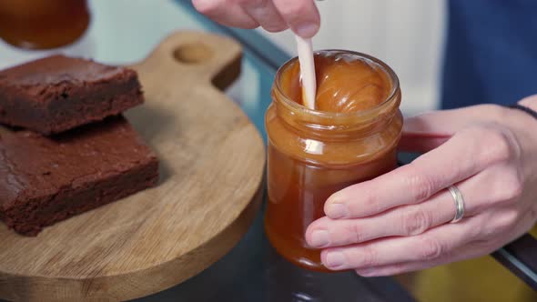 Female Hands Stir a Jar of Homemade Salted Caramel