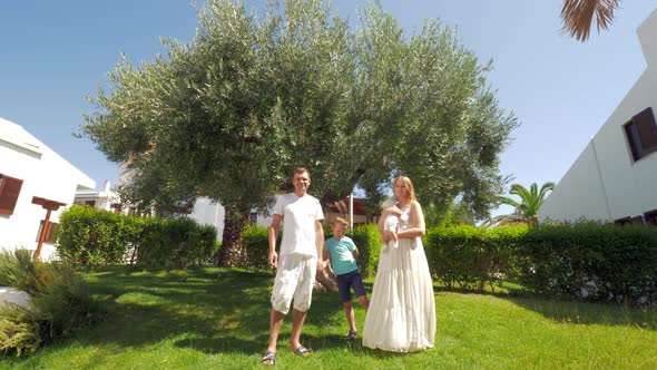 Young family with two children near olive tree in the garden