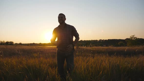 Close Up of Happy Man Running Through Grass Field with Sunset at Background