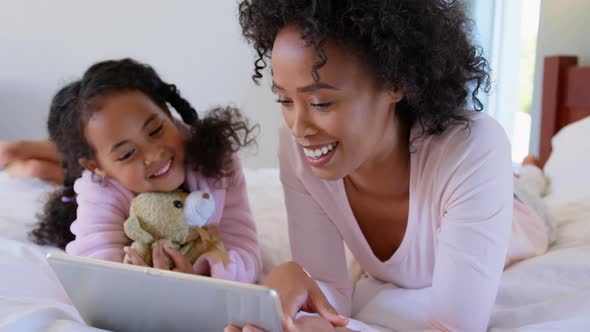 Front view of black mother and daughter using digital tablet at comfortable home 4k