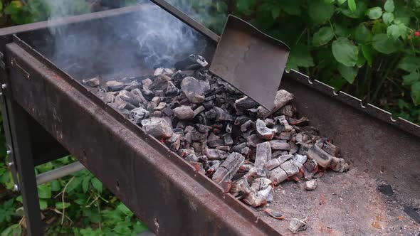 Burning coals and wood in the brazier turned over and prepared with coal shovel