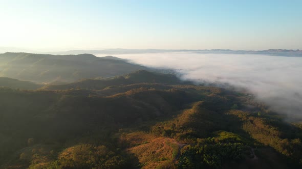 4K Flying through the clouds above mountain tops. Tropical forest with smoke and fog.