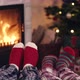 Couple feet in christmas woolen socks near fireplace decorated tree tee cup in backg - VideoHive Item for Sale