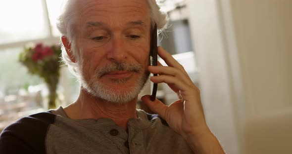 Senior man talking on mobile phone at home 4k