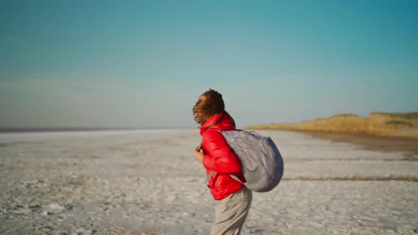 Slow Motion Happy Young Woman Traveler in Red Jacket Running and Jumping on Salt Desert Dry Coast of