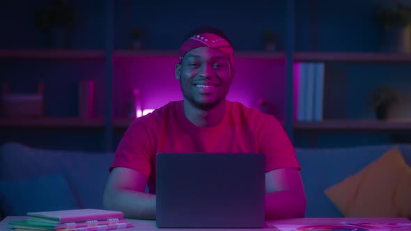 African Freelancer Guy At Laptop Smiling To Camera At Home