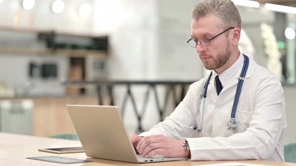 Male Doctor Working on Laptop in Office 