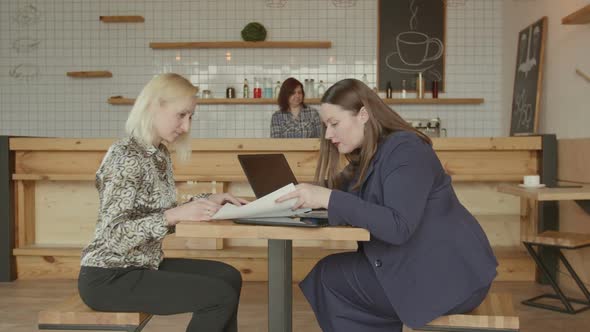 Women with Documents and Gadgets Working in Cafe