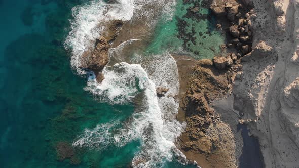 Top-down static view over sea waves crashing on rocky coast of Porto dos Frades, Madeira.