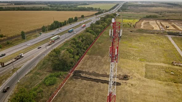 Cell Site of Telephone Tower with 5G Transceiver By Highway with Traffic Cars