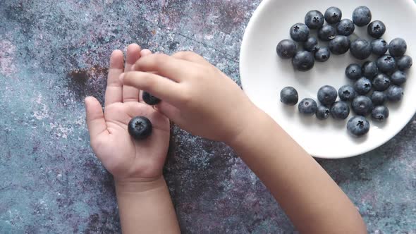 Top View of Child Putting Fresh Blue Berry on Hand