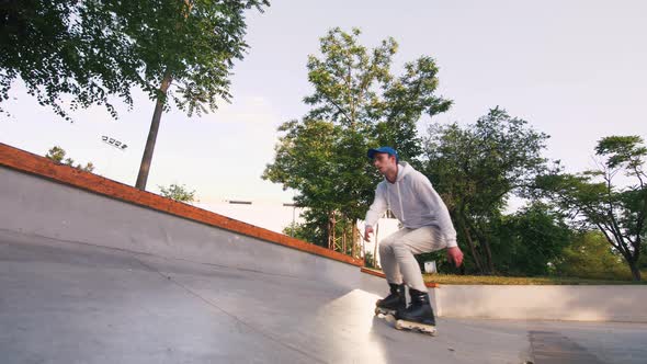 Aggressive Inline Roller Skater Doing Tricks in Concrete Skatepark Outdoors Slow Motion Low Angle