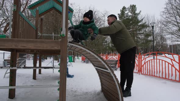 Dad Helps Son to Climb a Children's Slide