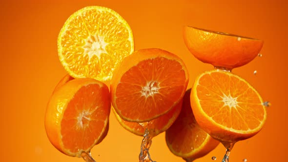 Super Slow Motion Shot of Flying Orange Slices and Splashing Water on Orange Background at 1000Fps