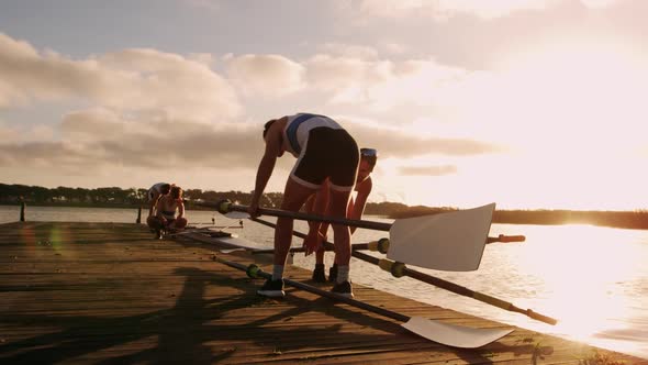 Male rower holding oars on jetty