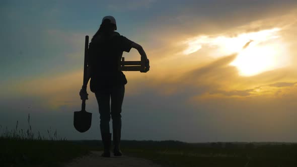 Silhouette Female Farmer Holding Shovel in His Hand Walking Across Green Field a Pile of Dirt Soil