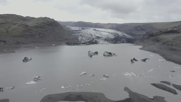 Aerial drone view over a lagoon, towards the Solheimajokull Glacier, in cloudy Iceland