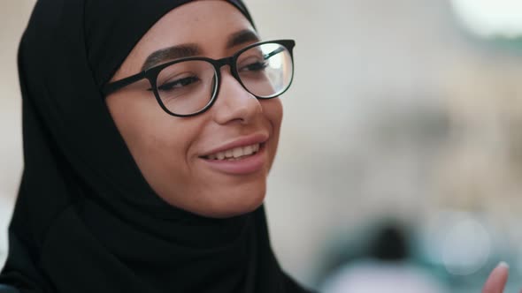 Close-up view of a positive arabian woman wearing national hijab is talking to someone