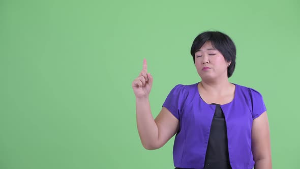 Stressed Young Overweight Asian Woman Pointing Up