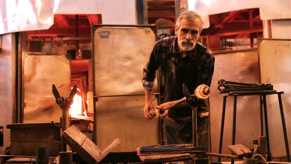 Glassblower shaping a molten glass