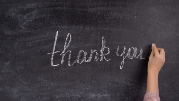 a woman's hand writes the phrase THANK YOU on a chalkboard