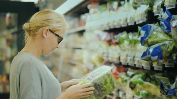 Woman in Glasses Selects Products in the Supermarket Fresh Vegetables Department