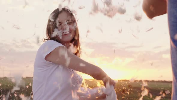 A Woman Is Beating Her Pillow with a Friend, Feathers Are Flying