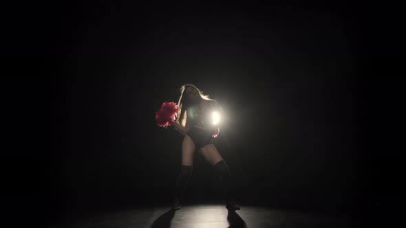 Energetic Dance of Cheering Performed By a Cute Cheerleader Holding Pompoms Against Backlit Black