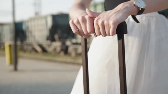 Female Hands Hold Suitcase Handles on Railway Platform