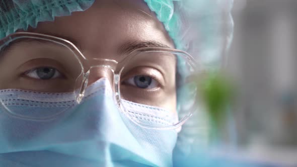 Close Up Of A Doctor's Eye. Doctor Laboratory Assistant Looks At A Test Tube With Green Material