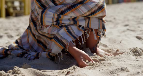 Teenage girl wrapped in blanket playing with sand 4k