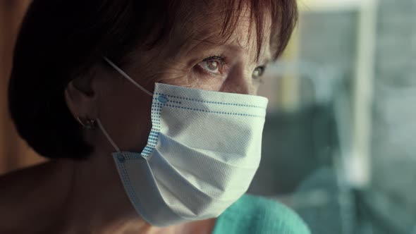 Elderly Woman in Face Mask Behind Window