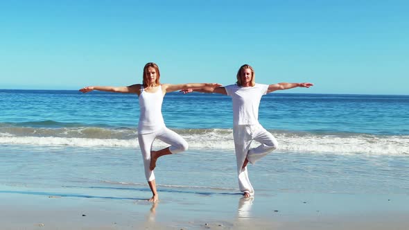 Couple performing yoga at beach