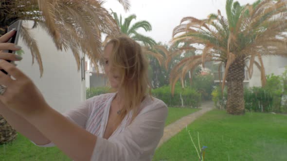 Cheerful woman making summer selfie on rainy day