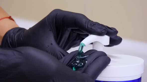 Close-up, Hands in Black Medical Gloves Squeeze Out a Cosmetic Product, Green Gel From a Dispenser