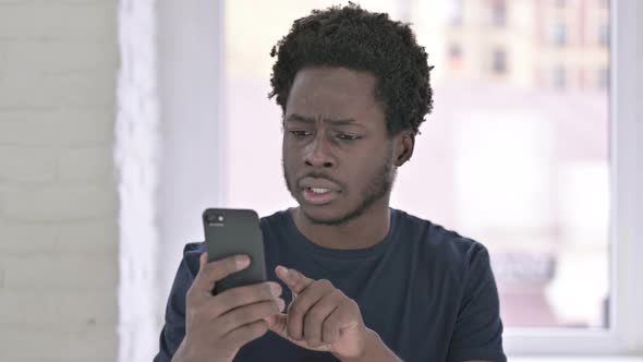 Portrait of Cheerful Young African American Man Celebrating on Smartphone