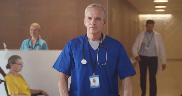 Portrait of Confident Male Doctor with Stethoscope Wearing Scrubs in Hospital Waiting Room