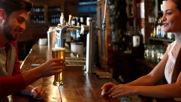 Barmaid interacting with male costumer while serving beer