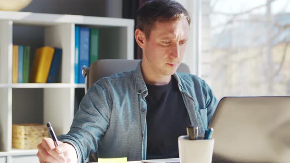 Young male entrepreneur works at home office at the computer.