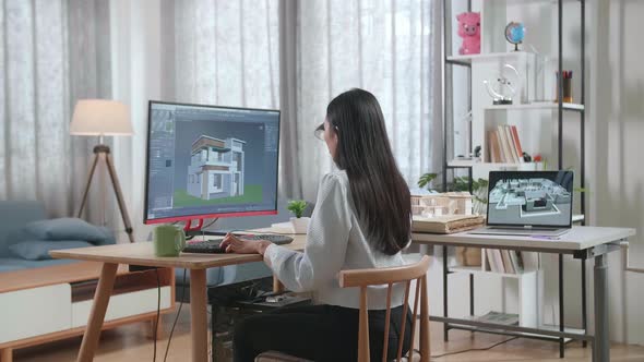 Asian Woman Engineer Rotate 3D House While Working On A Desktop At Home. Cyber Games House Design