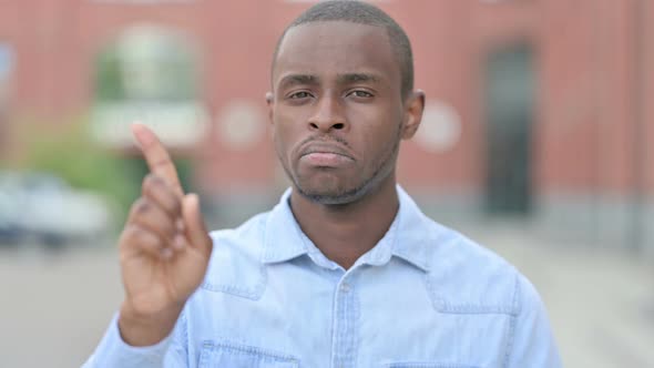 Outdoor Portrait of Young African Man Saying No with Finger Sign
