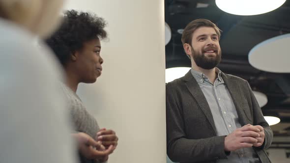 Businessman and Businesswoman Laughing and Chatting with Colleagues