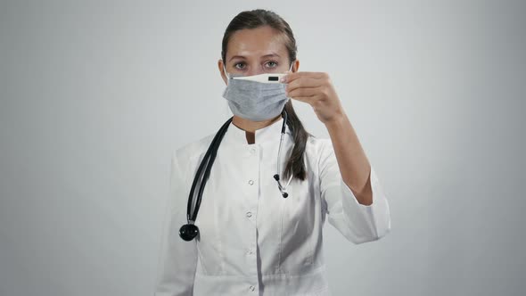 Doctor in medical mask with thermometer