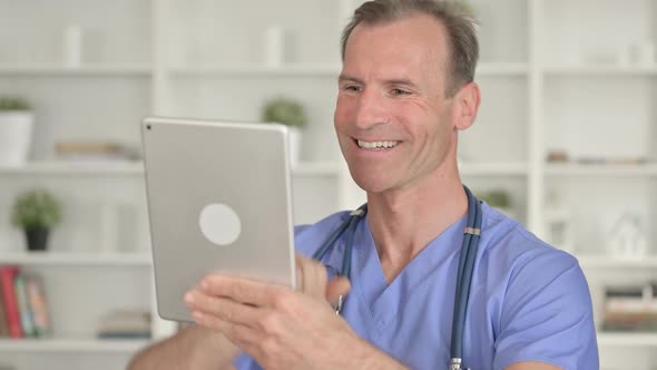 Portrait of Middle Aged Doctor Doing Video Chat on Tablet